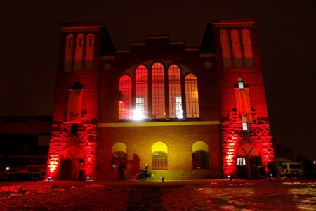 Die Fassade des Postbahnhof in Berlin wird am Abend Rot und gelb angeleuchtet