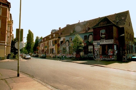 Die Außenfassade des Cafe Glocksee Hannover mit vielen Graffitis. Vor der Location liegt eine Straße wo einige Autos parken