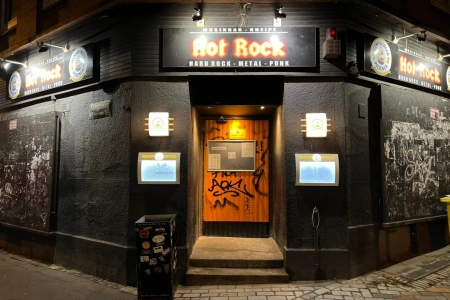 Der Eingangsbereich des Hot Rock Kiel mit 2 Treppenstufen, dem Logo un der gelben Tür