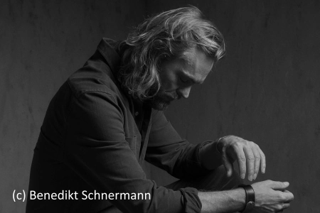 Nachdenklich sitzt der Musiker Ingo Pohlmann seitlich zur Kamera. Das Bild ist ich schwarz weiß gehalten.