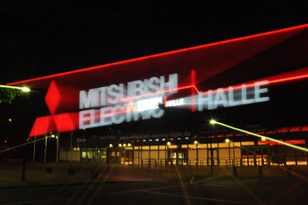 Das große leuchtende Logo am Eingangsbereich zur Mitsubishi Electric Halle Düsseldorf bei Nacht