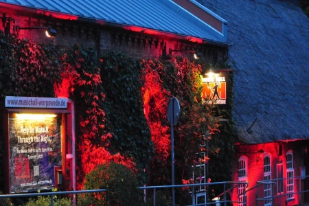Das Bild zeigt das Gebäude der Music Hall Worpswede in rotes Licht getaucht