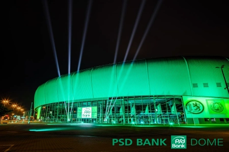 Der PSD BANK DOME Düsseldorf erinnert in seiner Form ein wenig an ein UFO. Die Fassade wird grün angeleuchtet und am Eingangsbereich schießen die Lichtkegel von sechs Strahlern in den dunklen Nachthimmel