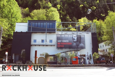 Die Aussenfassade des Rockhouse Salzburg mit der Straße und einem großen Konzertbanner