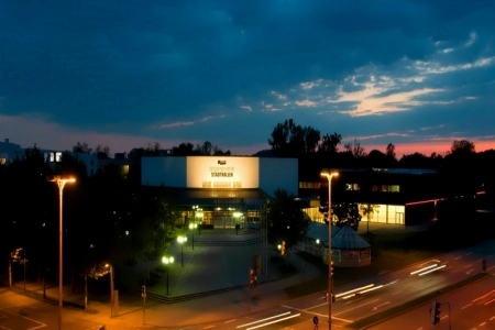 Bei Nacht sind die Stadthalle Deggendorf hell beleuchtet. Auf der Straße vor der Location herrscht Ruhe, kein Auto ist zu sehen.