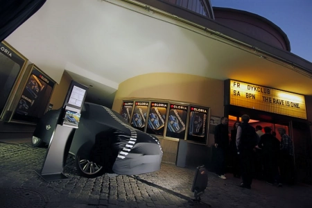 Im Eingangsbereich des Gloria Regensburg steht ein abgedecktes Auto, der Eingang ist beleuchtet.