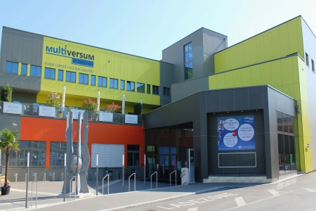 Das Multiversum Schwechat Wien ist ein modernes Multifunktionsgebäude. Die Fassade ist überwiegend in gelb gehalten. Zu sehen ist der große Eingangsbereich