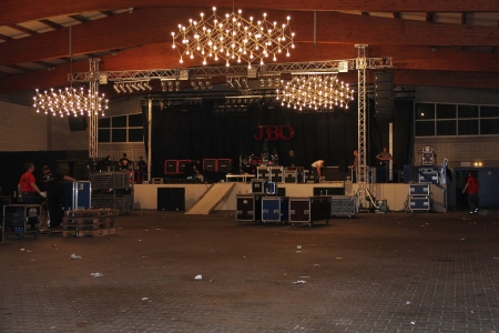 Die Bühne im Innenraum der Sommerfesthalle Otterstadt. Darüber hängen Kronleuter und die Techniker bauen gerade für den Auftritt der Band J.B.O. auf.