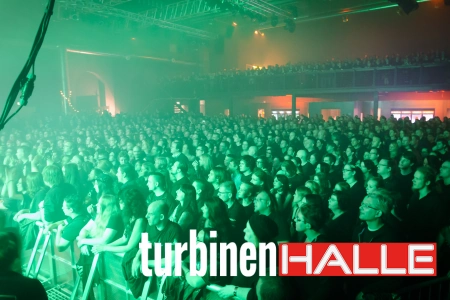 Durch die Scheinwerfer der Halle ist das Publikum in der Turbinenhalle Oberhausen in grünes Licht getaucht. Dicht an dicht stehen sie bei Konzerten