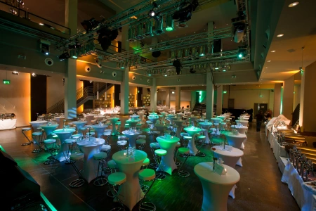 Festlich gedeckte Stehtische in der Union Halle Frankfurt. Der Saal ist in ein dezentes feierliches Licht getaucht. 