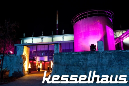 Das Kesselhaus München besticht durch seine charakteristische Bauweise und ist nachts in lila und blau beleuchtet. Die Halle ist so bei Veranstaltungen schon von Weitem zu erkennen.