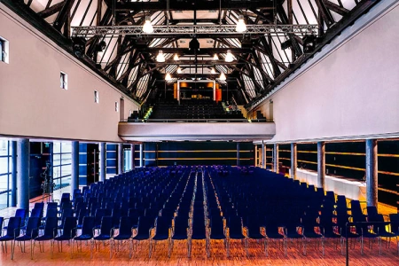 Ein Blick in den großen Saal des Kulturhaus Laupheim. Hier stehen Stuhlreihen mit blauen Polstern im Parkett.