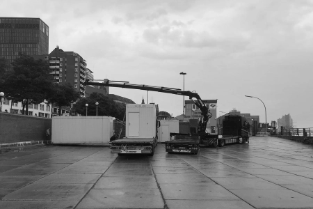 Ein großer Kran stellt die ersten Container am Hafen auf. Diese sind besonders wichtig für unsere Art der Coronahilfe