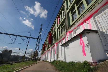 Die Fassade der MeetFactory Prag ist bunt bemalt. Das Gebäude liegt direkt an einer Bahnstrecke.