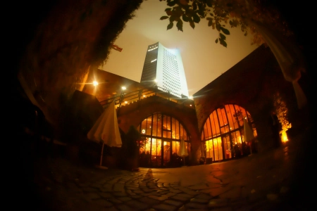 Die Moritzbastei Leipzig ist bei Nacht beleuchtet. Die Lichter spiegeln sich auf den nassen Steinen des Vorplatzes