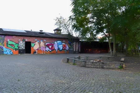 Der Vorplatz der Chemiefabrik Dresden ist mit Kopfsteinpflaster ausgelegt. Die Tür des flachen bunt bemalten Gebäudes steht weit offen