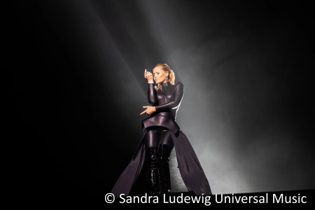 Die Sängerin Helene Fischer steht im schwarzen Kleid auf der dunklen Bühne. Vieles erwartet die Fans auf der Helene Fischer Rausch Tour 2023