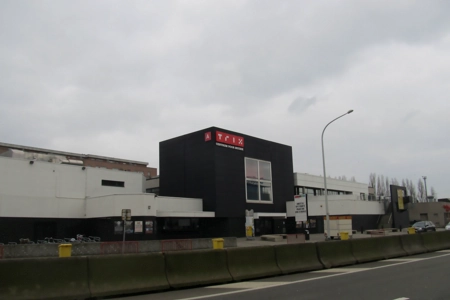 Ein Blick von der Straße aus auf das TRIX Antwerpen. Das Gebäude hebt sich durch seine schwarze Farbe deutlich von der Umgebung ab