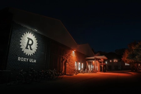 Hell strahlt das Logo des Roxy Ulm an der Fassade des Gebäudes bei Nacht.