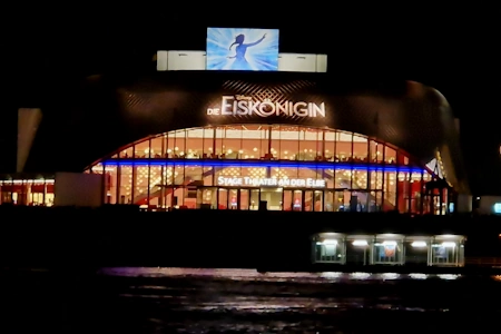 Die 12 Meter hohe Glasfassade des Stage Theater an der Elbe Hamburg leuchtet hell bei Nacht