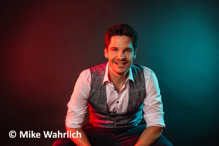 Der Schweizer Comedian Alain Frei sitzt locker auf einem Stuhl. Er hat gut lachen, denn es geht bald auf seine Alles Neu Tour